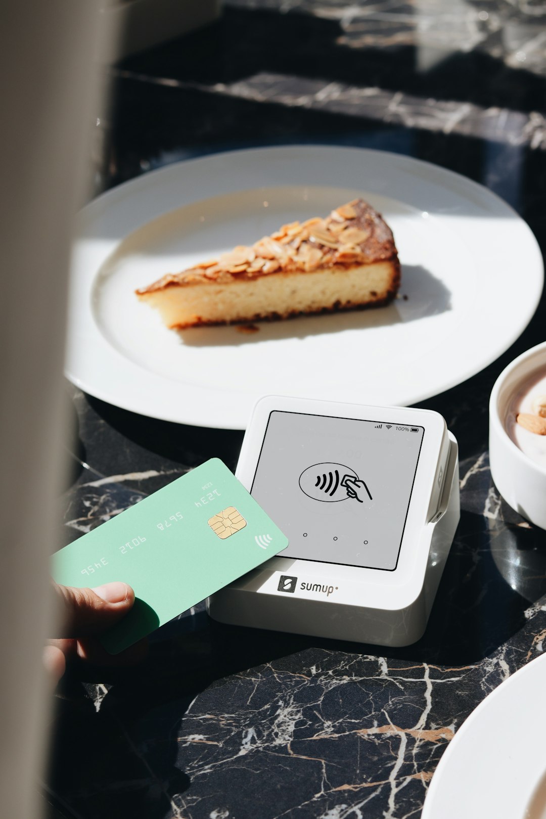 A SumUp card reader is placed on a table, ready to accept contactless payments. The setup is ideal for small businesses and cafés, offering a sleek and efficient way for entrepreneurs to accept payments.